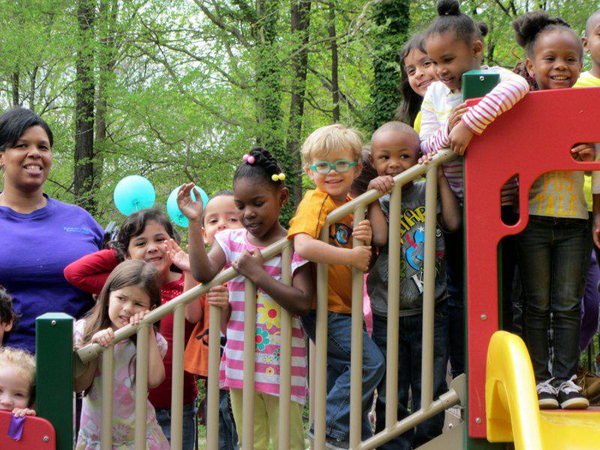 Students and their families celebrate at the ribbon cutting ceremony for the Raleigh preschool's new playground.