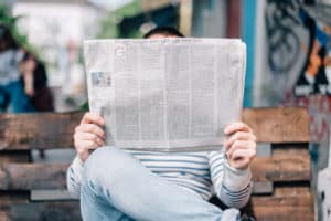 Picture of a person reading a newspaper learning about local Raleigh businesses
